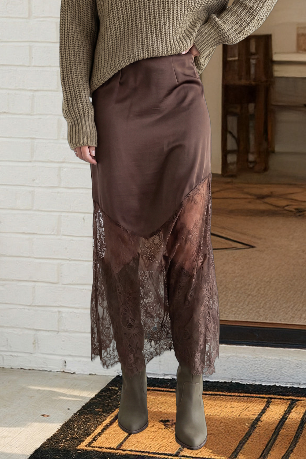 Person wearing a brown sweater and skirt standing on a doormat.