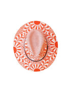 A top-down view of a fedora hat featuring an artisan painted vibrant orange and white sunburst pattern on the brim and a textured light pink crown. Crafted in Oaxaca, Mexico.