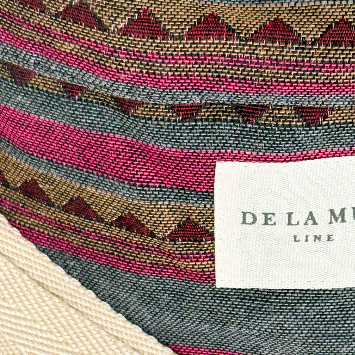Close-up of the woven pink, teal and burgundy stripes with triangle border and De La Mur label