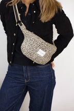 Beige and black leopard jacquard fanny pack worn crossbody over a black jacket