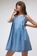 Woman wearing a blue denim dress against a plain background