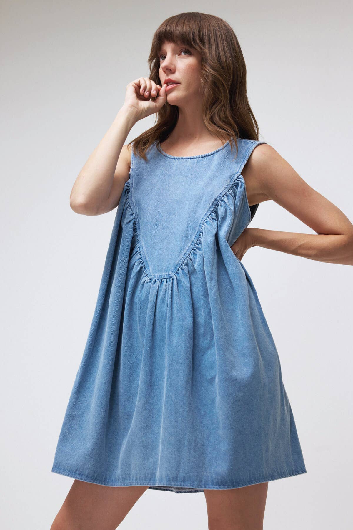 Woman wearing a blue denim dress against a plain background