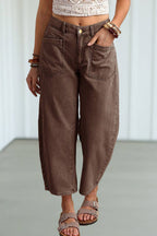 A person wearing brown wide-leg cropped jeans with a relaxed, baggy fit, paired with a cream crochet top and brown sandals.