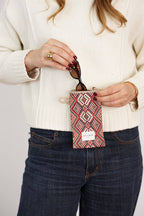 Red, green and cream geometric jacquard glasses case held by a woman in a cream sweater and jeans, shown for size