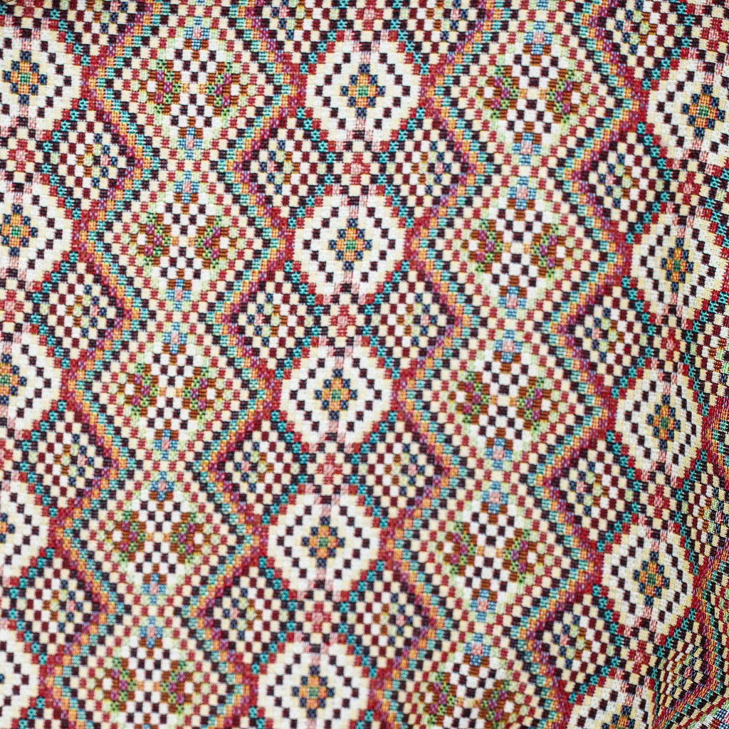 Close-up of the woven jacquard pattern on the red, green and cream geometric jacquard glasses case