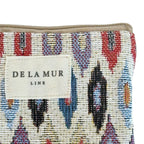 Close-up of the De La Mur label on the multicolor ikat jacquard glasses case with beige trim