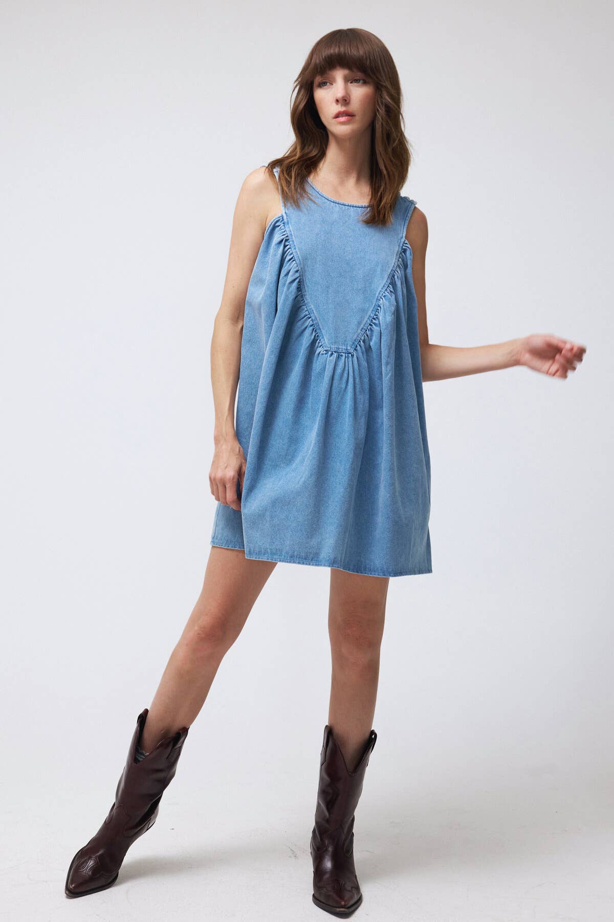 Woman wearing a blue dress with brown boots on a white background
