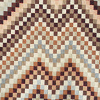 Close-up of the woven zigzag jacquard pattern on the brown and beige zigzag jacquard squared makeup bag