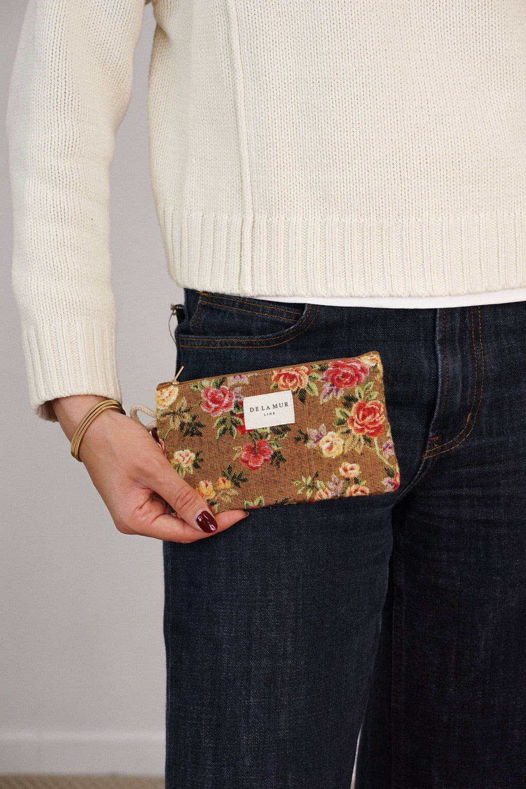 Mustard and red floral jacquard small pouch and coin purse held by a woman in a cream sweater and jeans, shown for size
