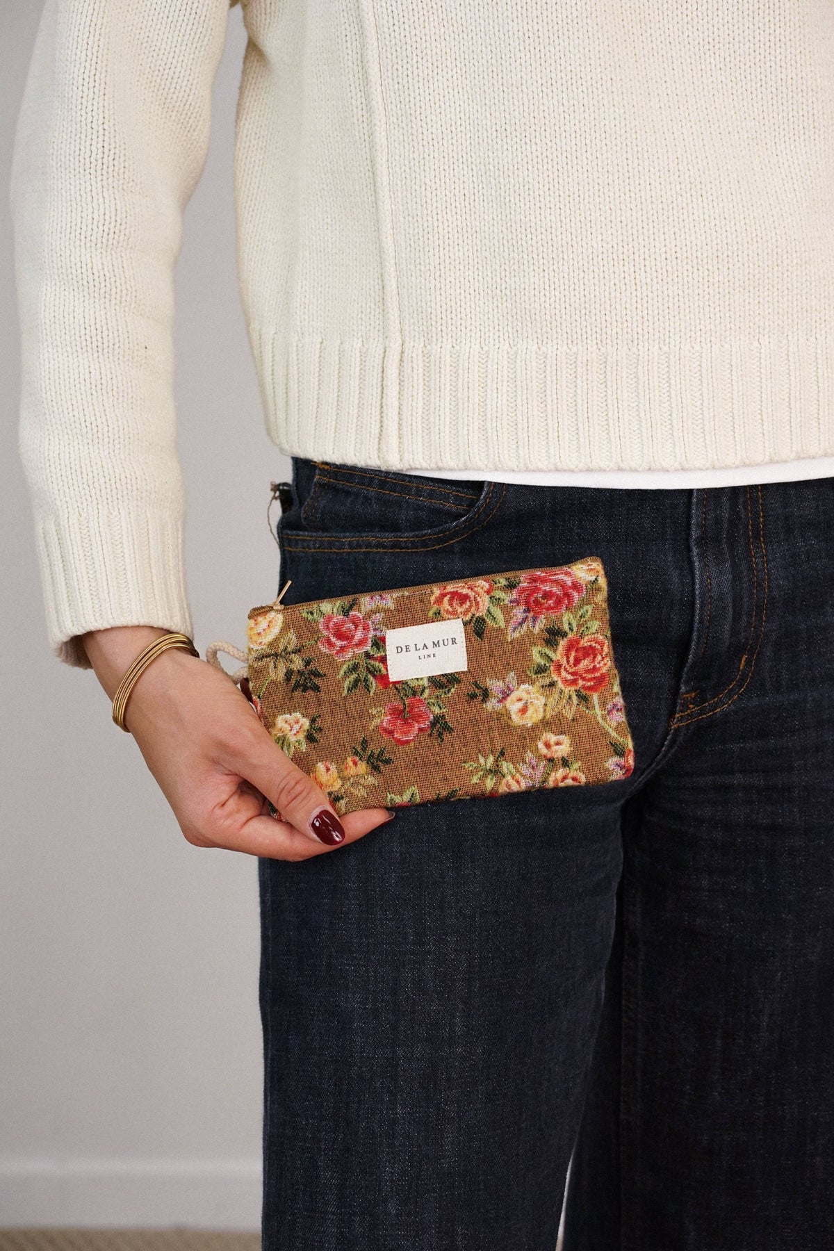 Mustard and red floral jacquard small pouch and coin purse held by a woman in a cream sweater and jeans, shown for size