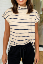 A woman wearing a cream-colored short-sleeve mock neck top with navy blue horizontal stripes, paired with black drawstring sweatpants.
