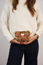 Mustard and red floral jacquard small makeup bag held by a woman in a cream sweater and jeans, shown for size