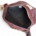 Pink and teal striped jacquard fanny pack unzipped to show the dark lining and inner pocket