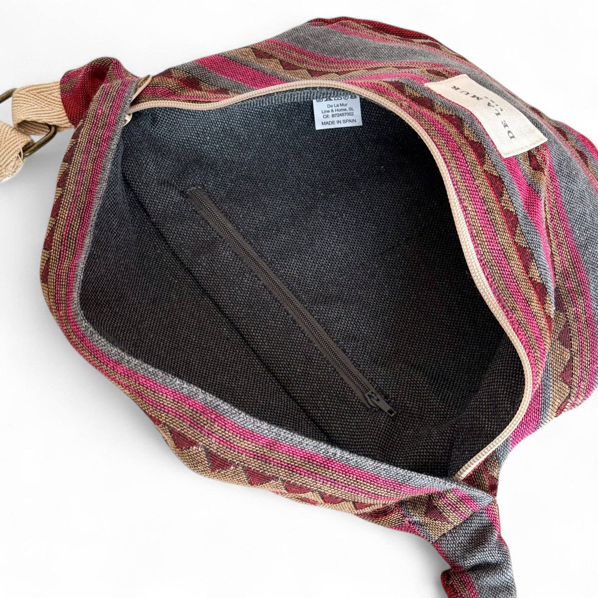 Pink and teal striped jacquard fanny pack unzipped to show the dark lining and inner pocket