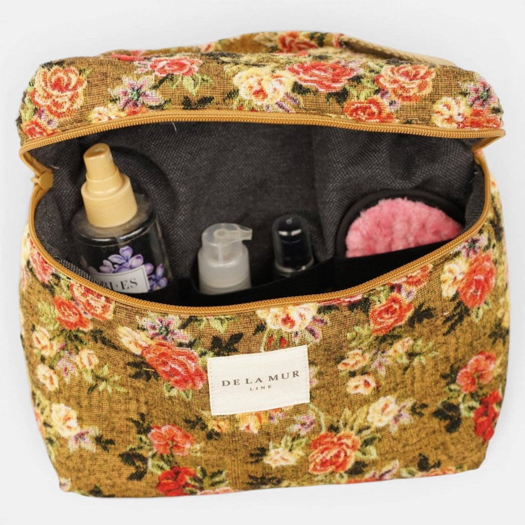 Large mustard and red floral jacquard squared toiletry bag unzipped, holding skincare bottles upright inside