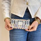 Multicolor ikat jacquard glasses case with beige trim held by a woman at her hip, shown for size