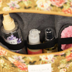 Close-up of the elastic loops holding bottles inside the large mustard and red floral jacquard squared toiletry bag