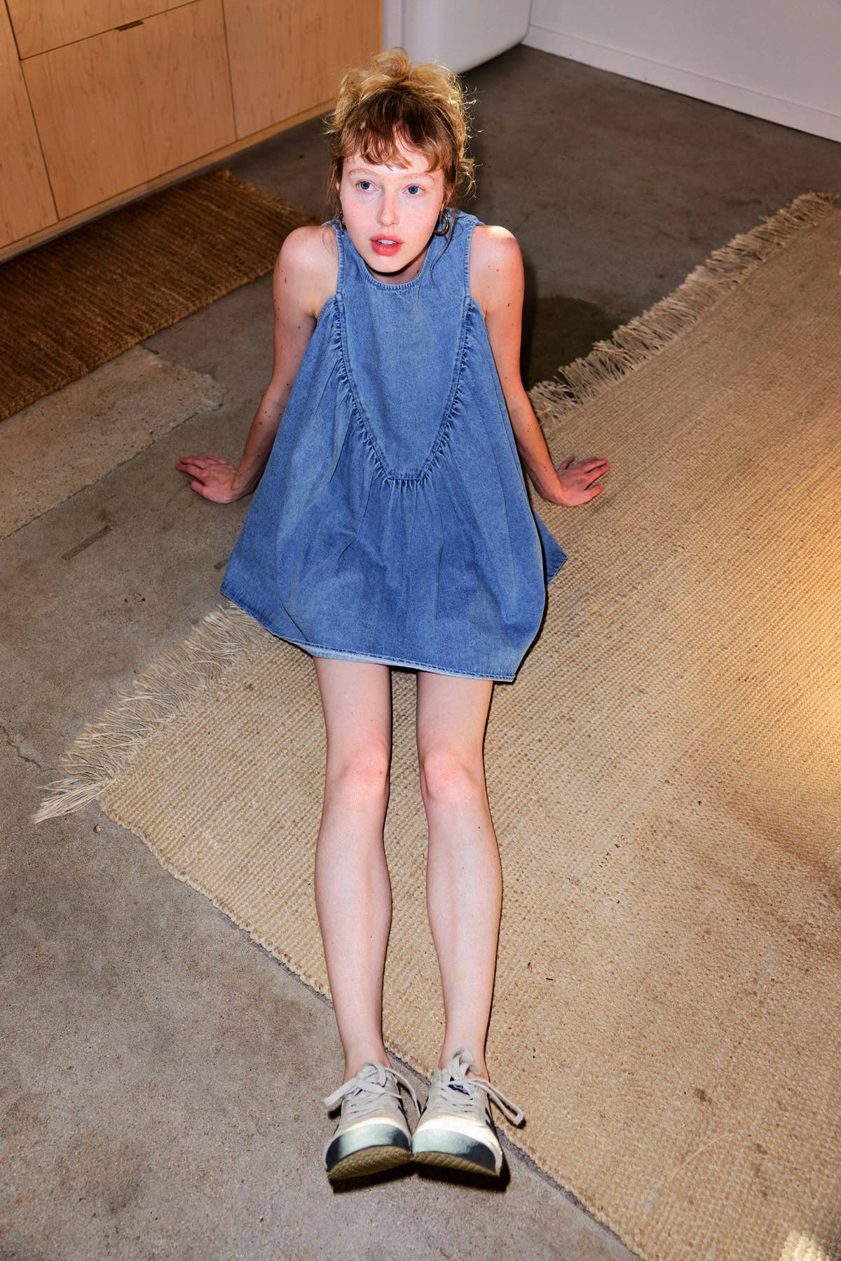 Young girl in a blue dress standing on a textured floor.