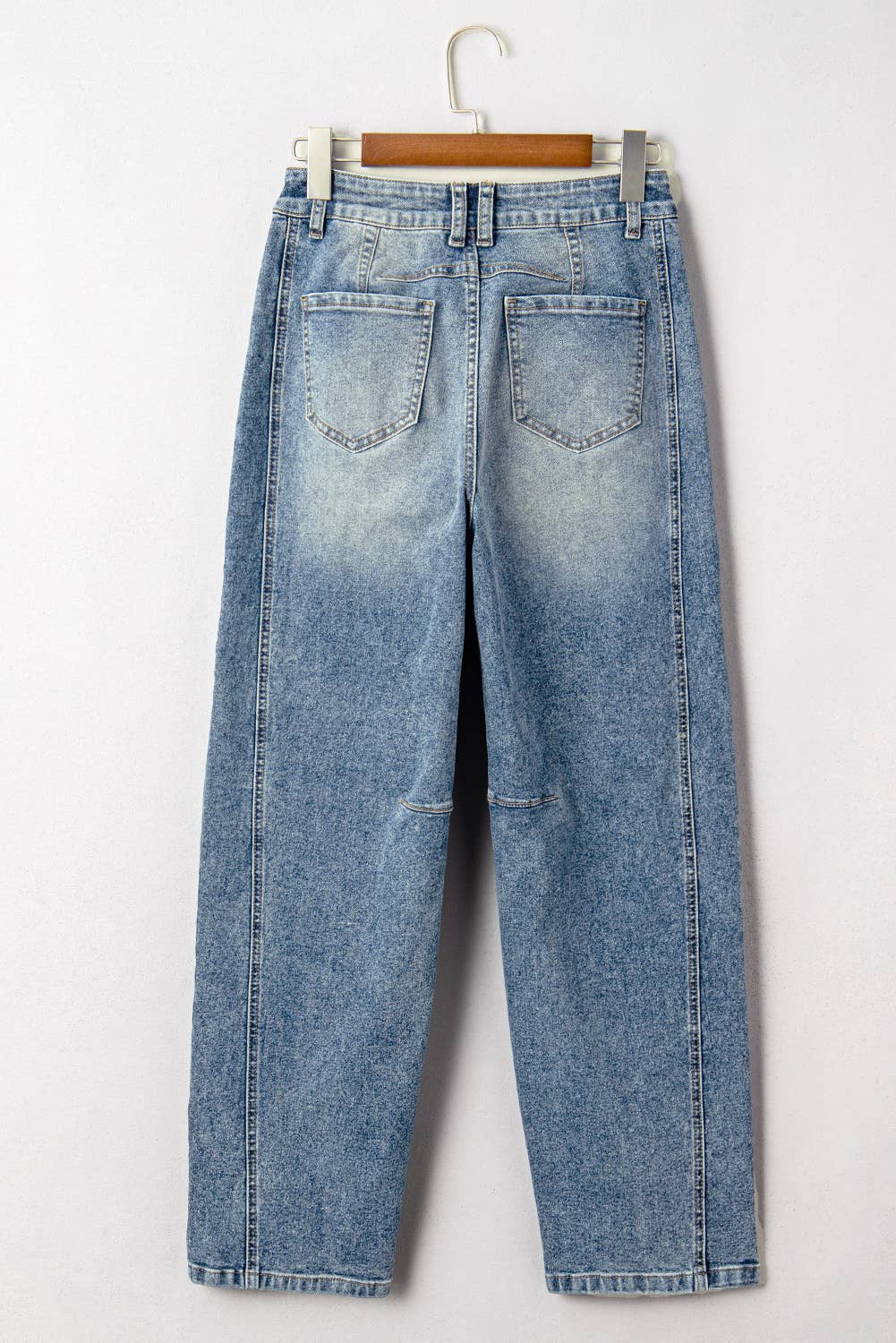 Pair of blue jeans on a hanger against a white background