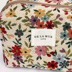 Close-up of the multicolor ditsy floral jacquard and De La Mur label on the squared makeup bag