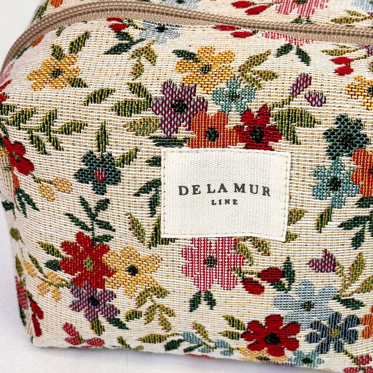 Close-up of the multicolor ditsy floral jacquard and De La Mur label on the squared makeup bag